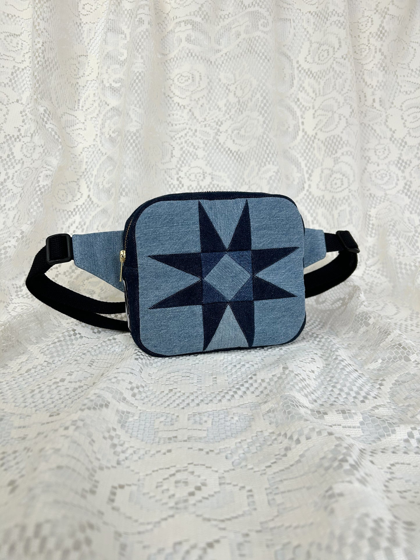 Two tone blue denim fanny pack with a patchwork star pattern on a white lace background