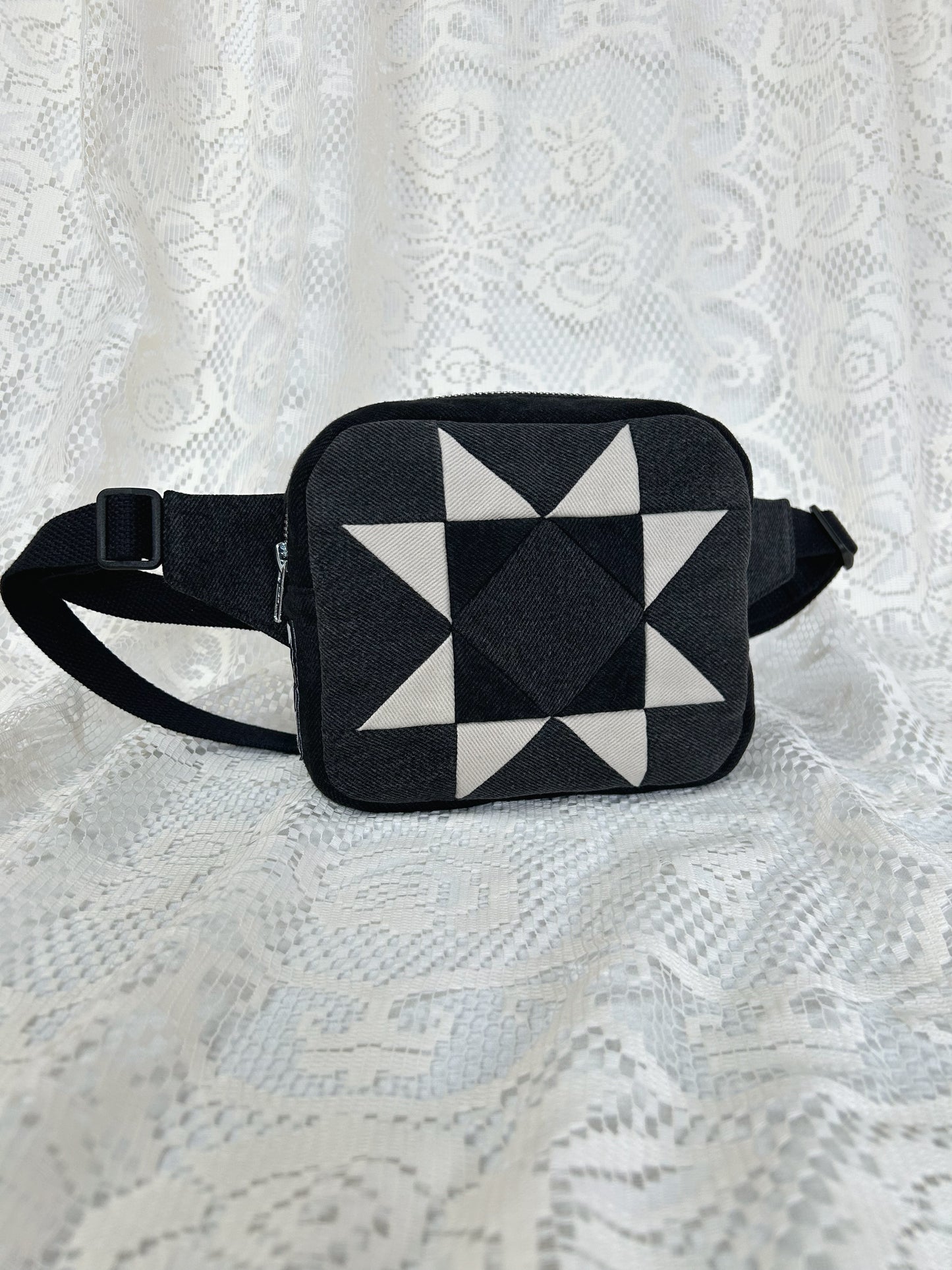 Grey, black and ivory denim fanny pack with a patchwork star pattern on a white lace background