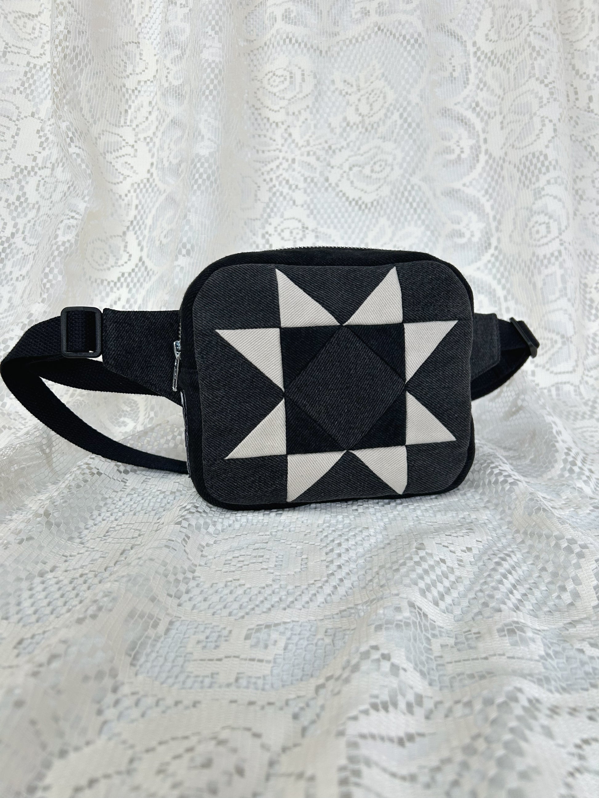 Grey, black and ivory denim fanny pack with a patchwork star pattern on a white lace background