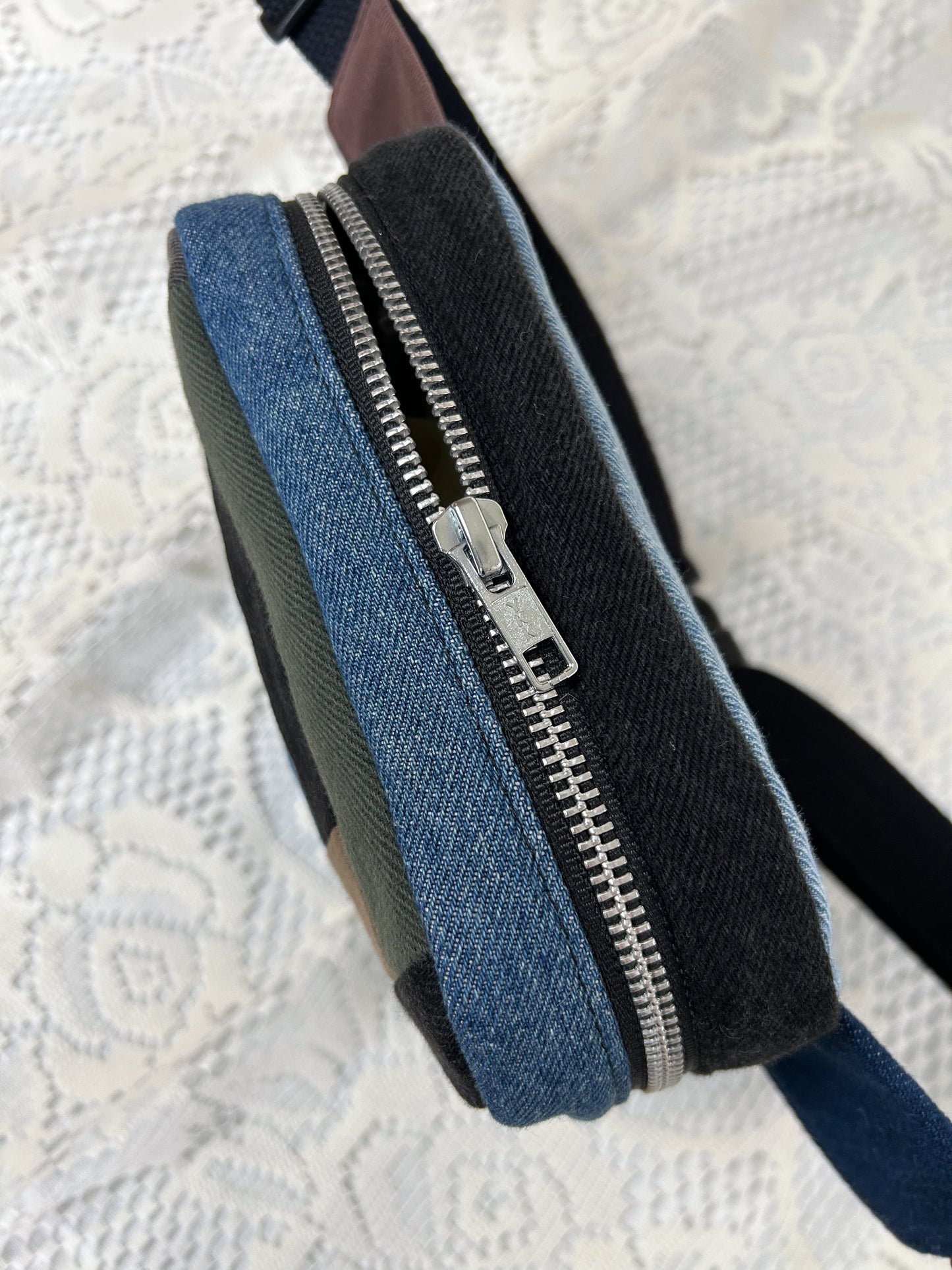Top view of the log cabin patchwork fanny pack showing the zipper on a white lace background