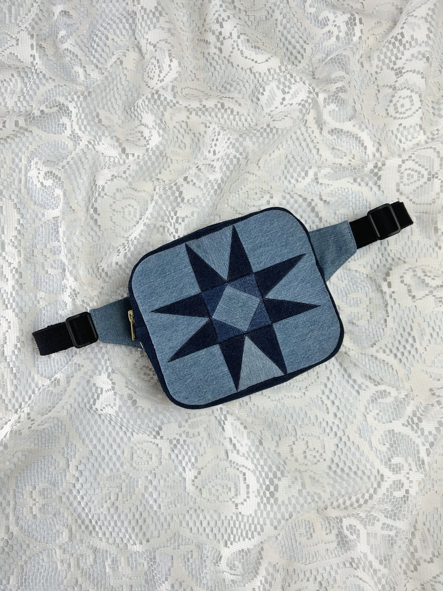 Two tone blue denim fanny pack with a patchwork star pattern on a white lace background
