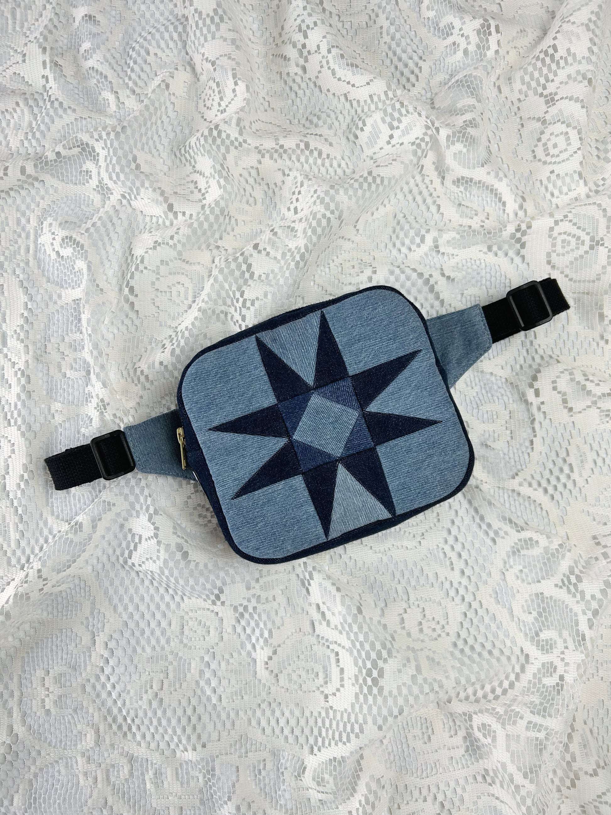 Two tone blue denim fanny pack with a patchwork star pattern on a white lace background