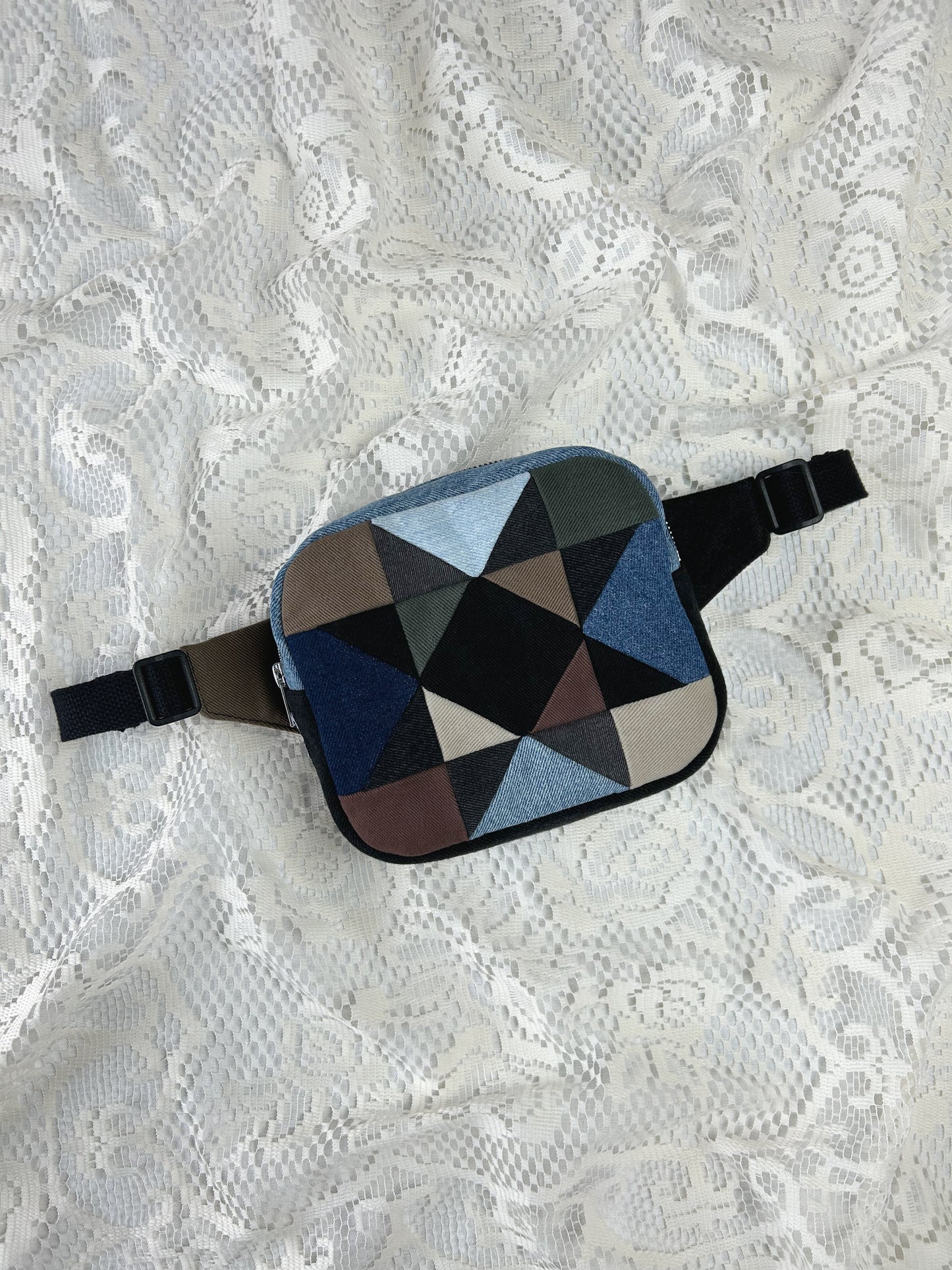 Multi-coloured denim fanny pack with a patchwork star pattern on a white lace background