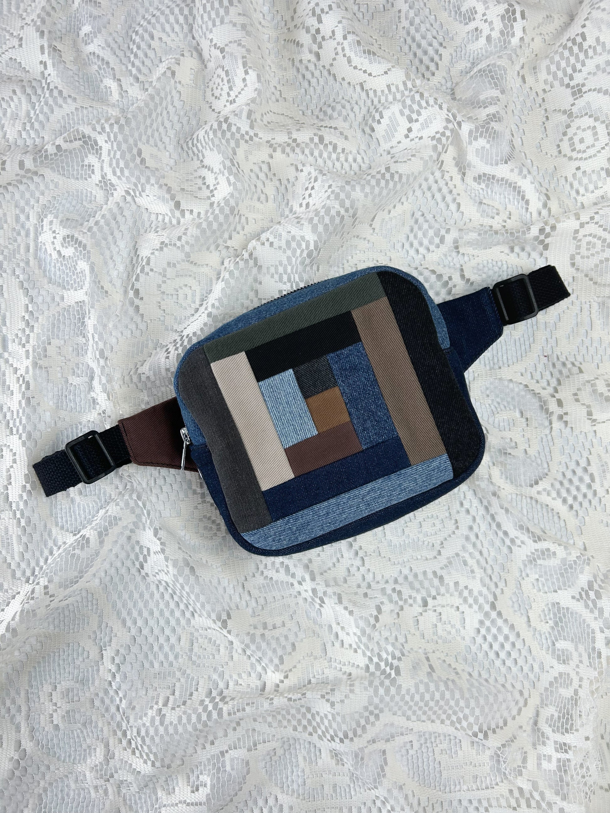 Fanny pack with a traditional log cabin patchwork design made using different colours and types of denim on a white lace background