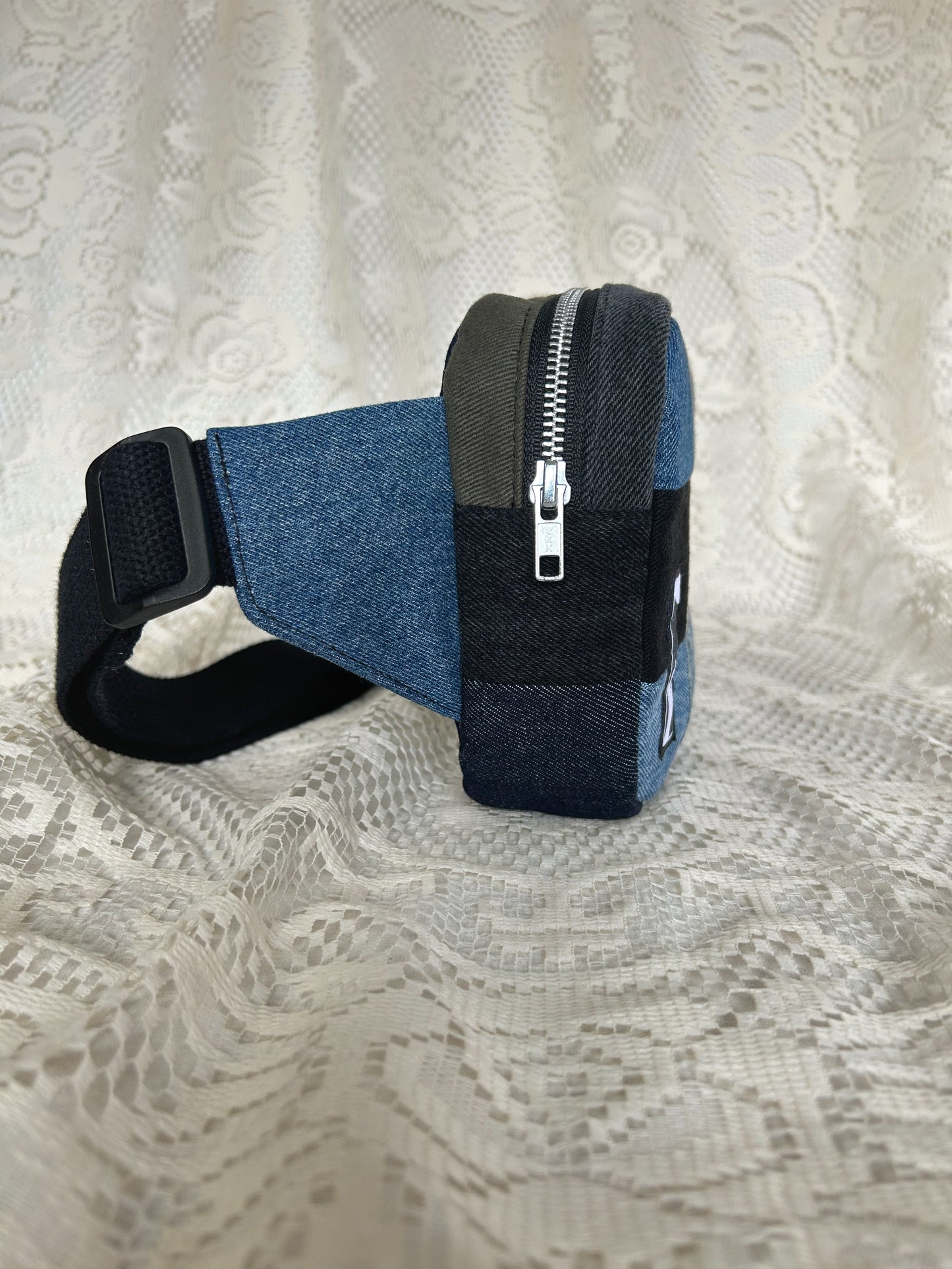 Side view of the fanny pack showing the aluminum zipper with an ivory lace backdrop