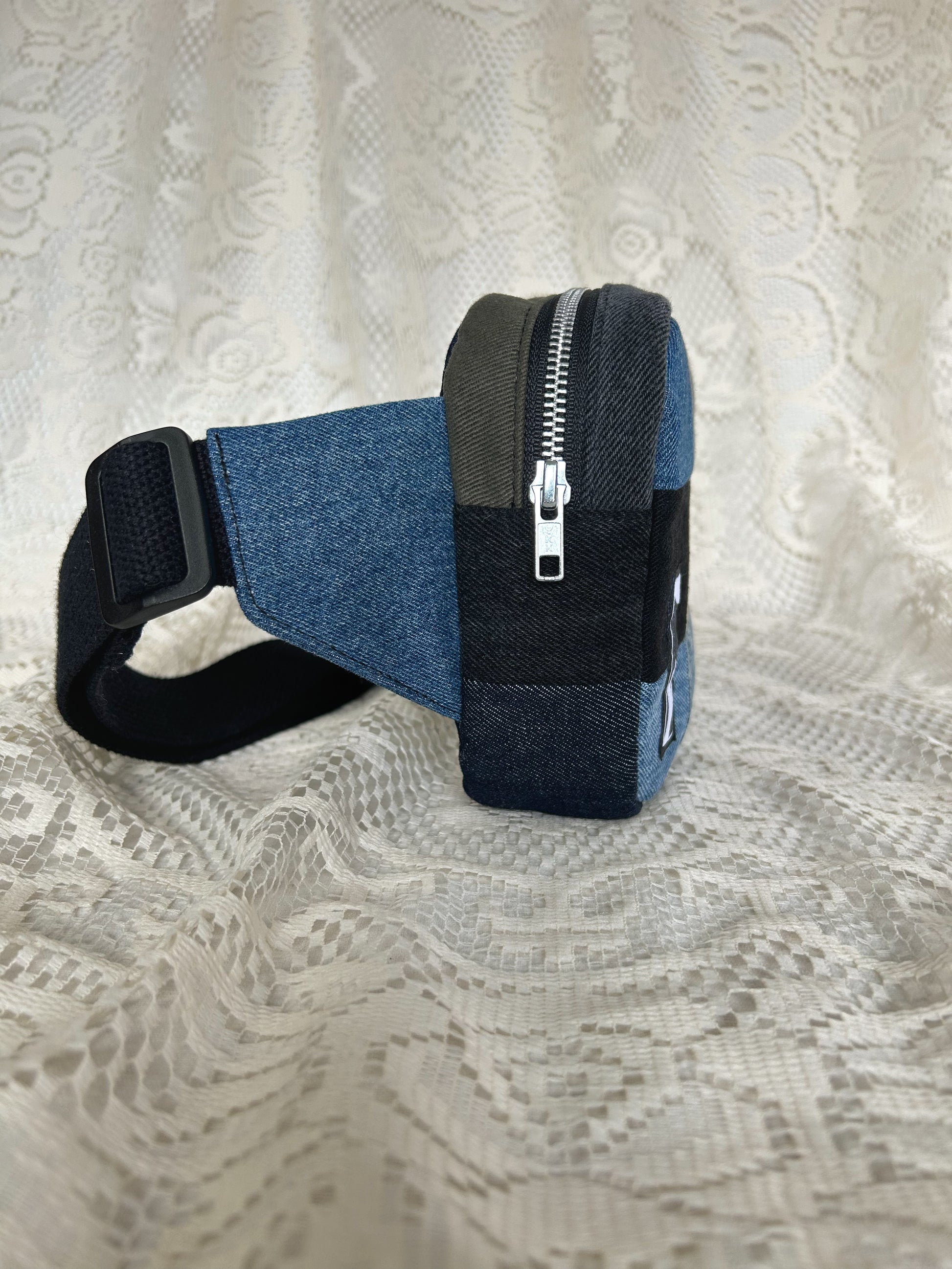 Side view of the fanny pack showing the aluminum zipper with an ivory lace backdrop