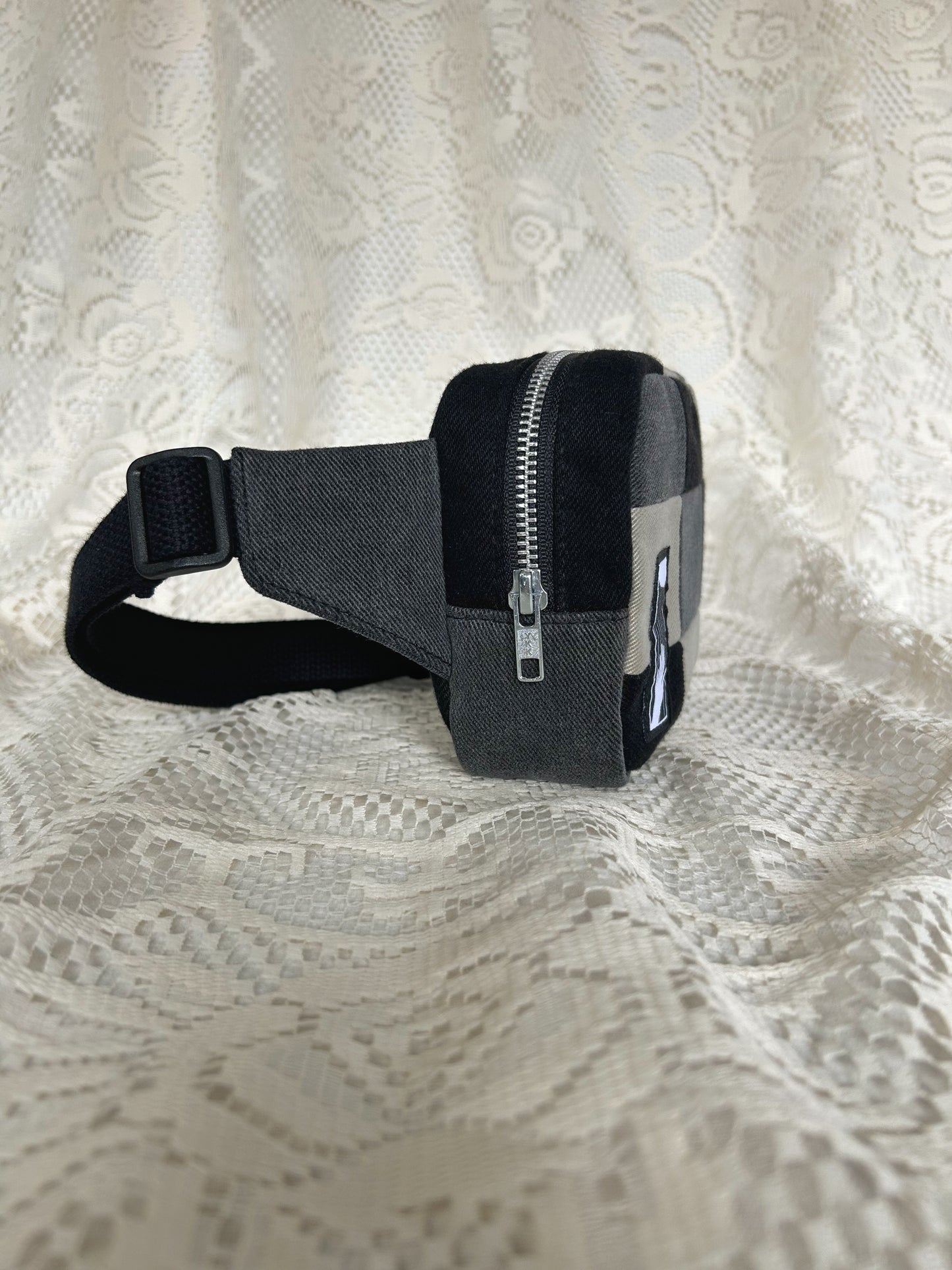Side view of the fanny pack showing the aluminum zipper with an ivory lace backdrop