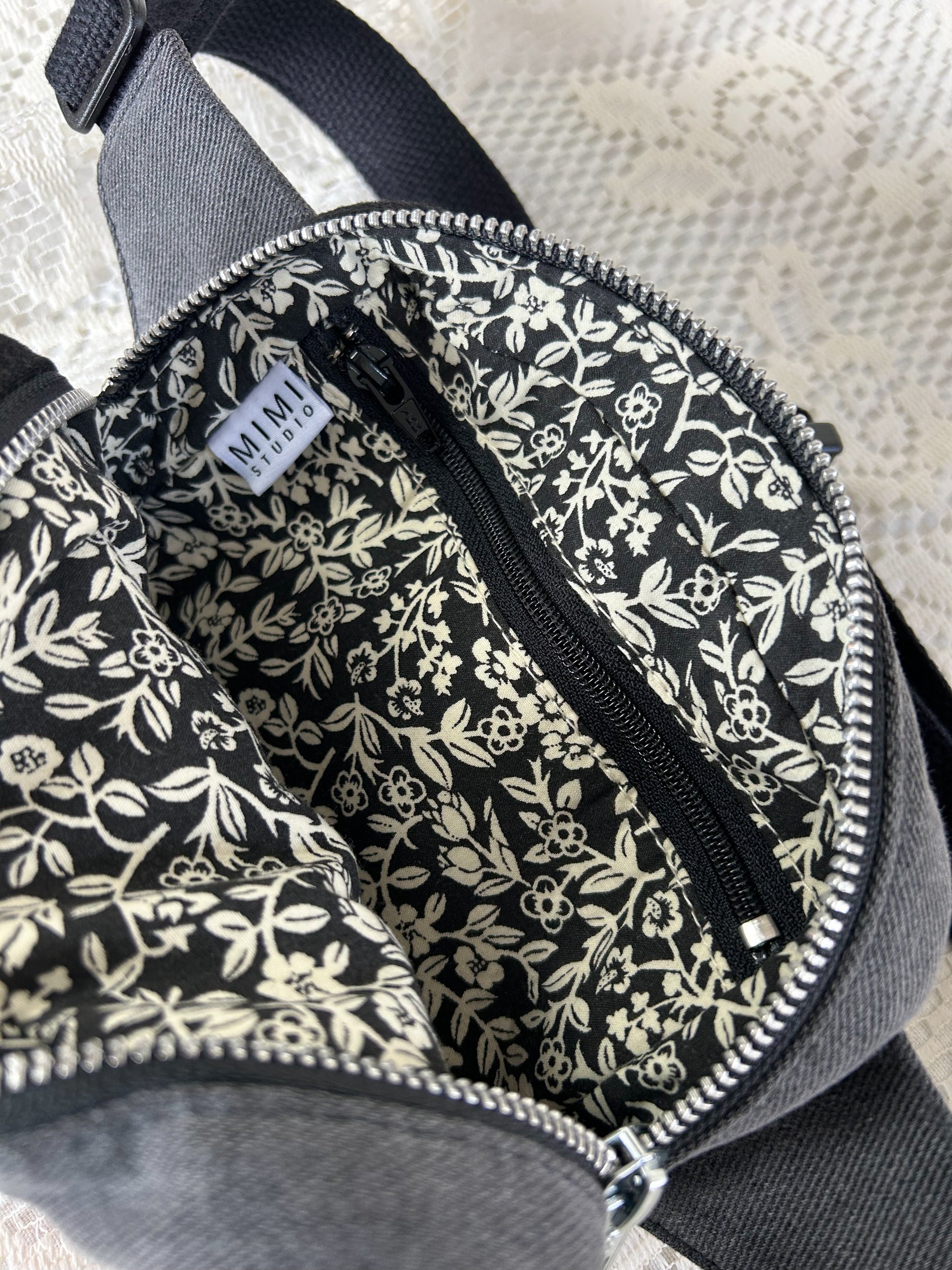 Black and ivory floral patterned interior lining of the fanny pack with a zippered pocket