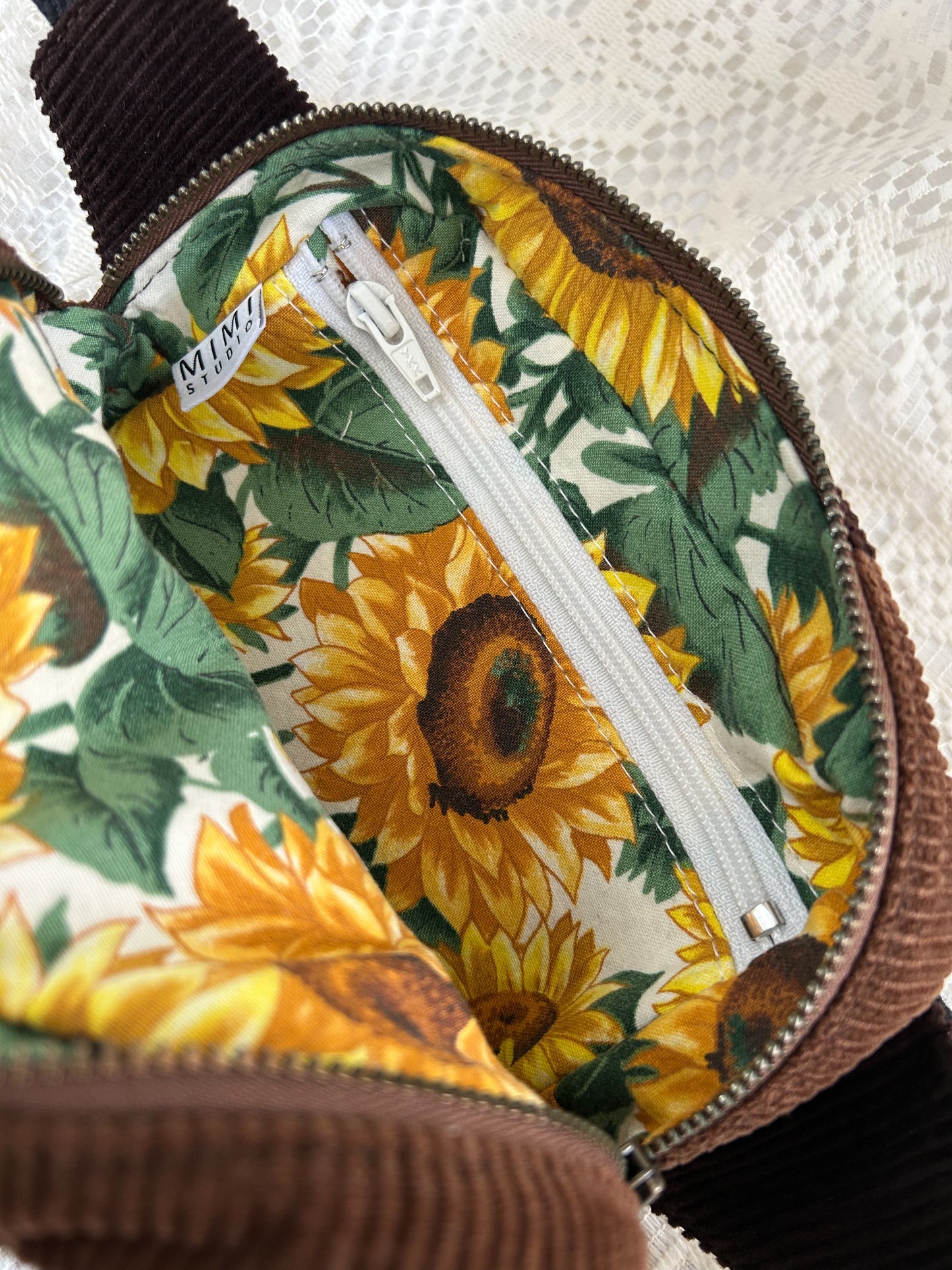 Sunflower patterned interior lining of the fanny pack with a zippered pocket