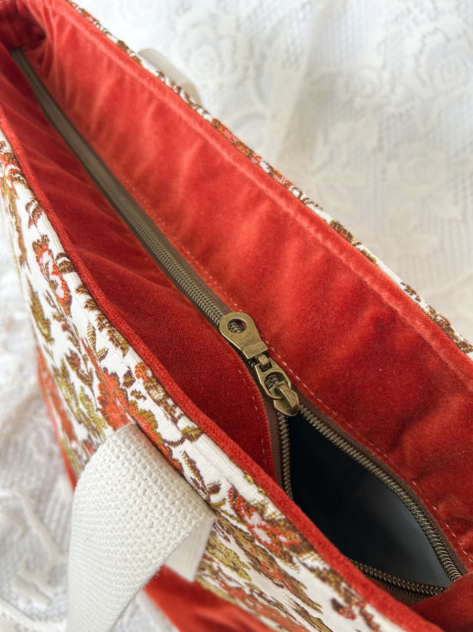 Top view of the same tote bag showing the antique brass coloured coil zipper with an ivory lace backdrop
