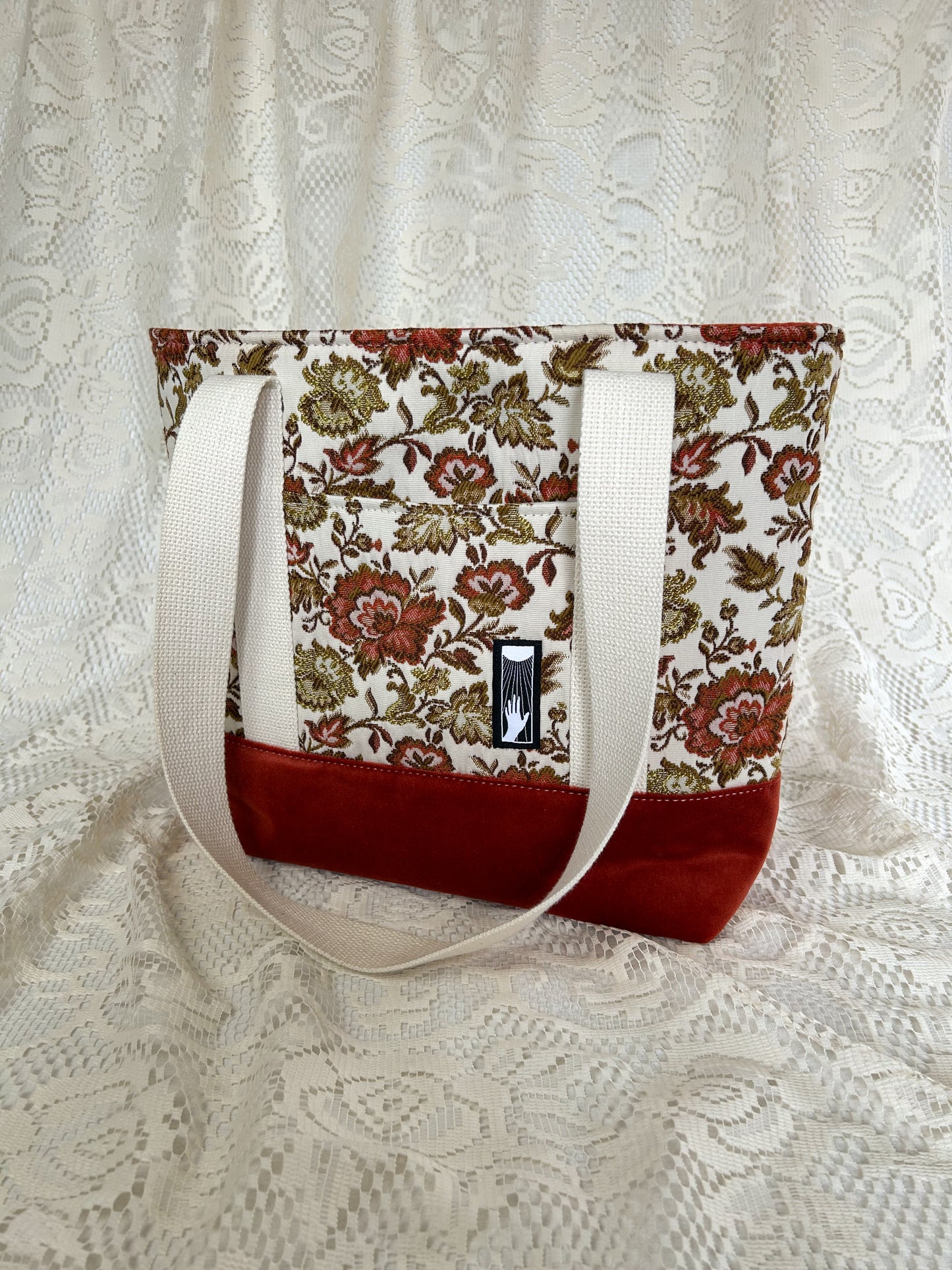Front angled view of the same tote bag on an ivory lace backdrop