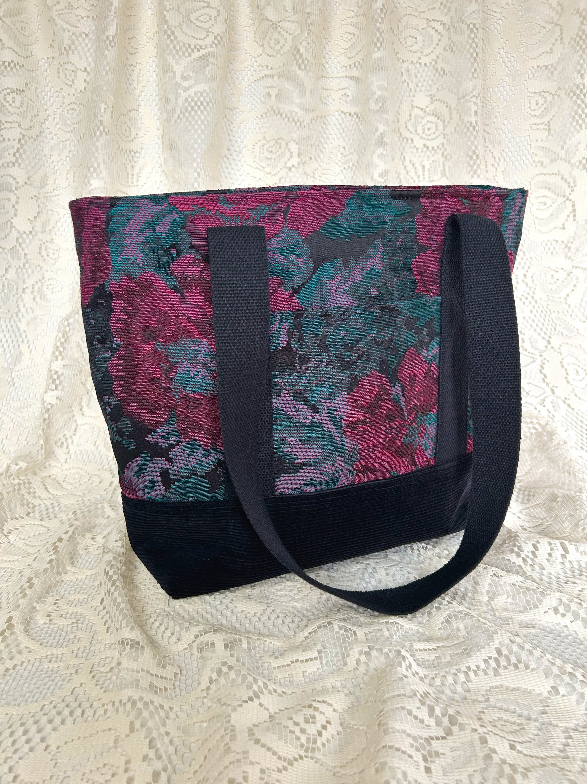 Front angled view of the same tote bag with an ivory lace backdrop