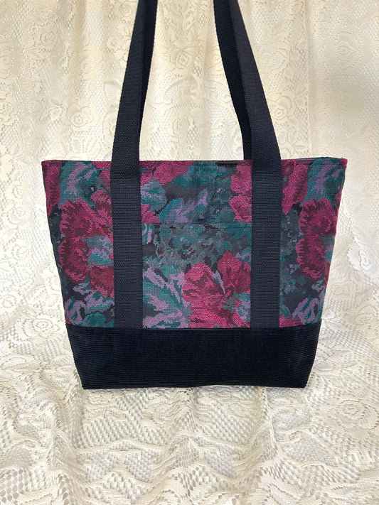 Tote bag made from burgundy, turquoise, and black floral fabric and black corduroy, with black cotton webbing straps with an ivory lace backdrop