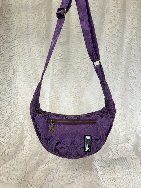 Front view of the purple damask fabric crescent moon bag with an ivory lace backdrop
