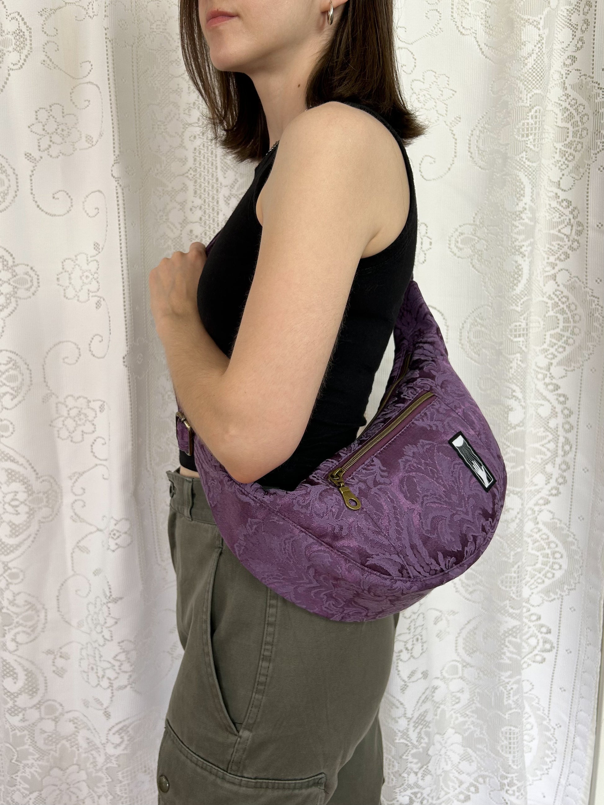 Woman wearing the crescent moon bag cross body in front of a white lace backdrop 