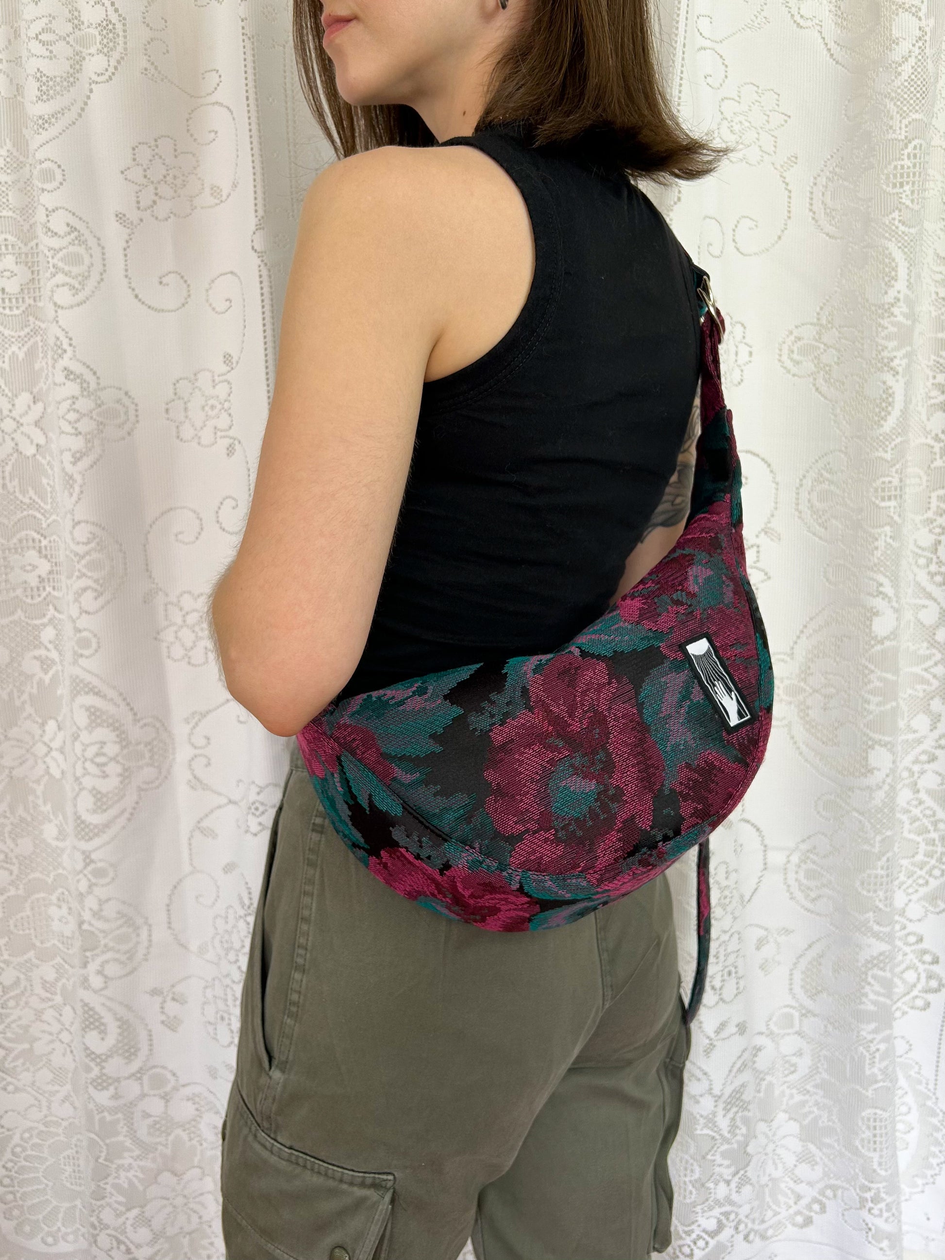 Woman wearing the crescent moon bag cross-body in front of a white lace backdrop