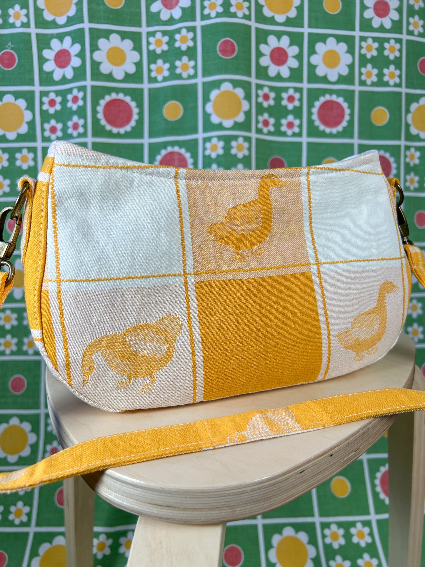 Closeup of the same handbag on a wooden stool in front of a floral backdrop