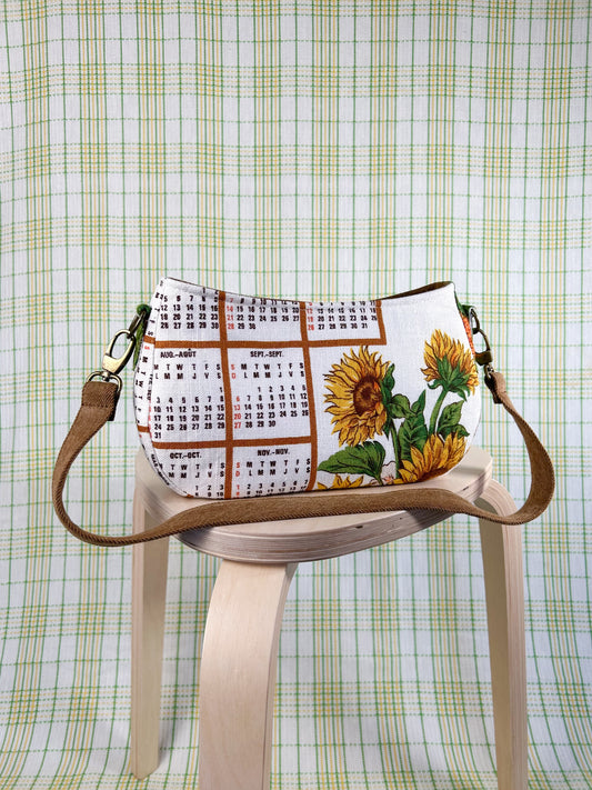 Handbag with sunflower and calendar design on a wooden stool against a plaid background
