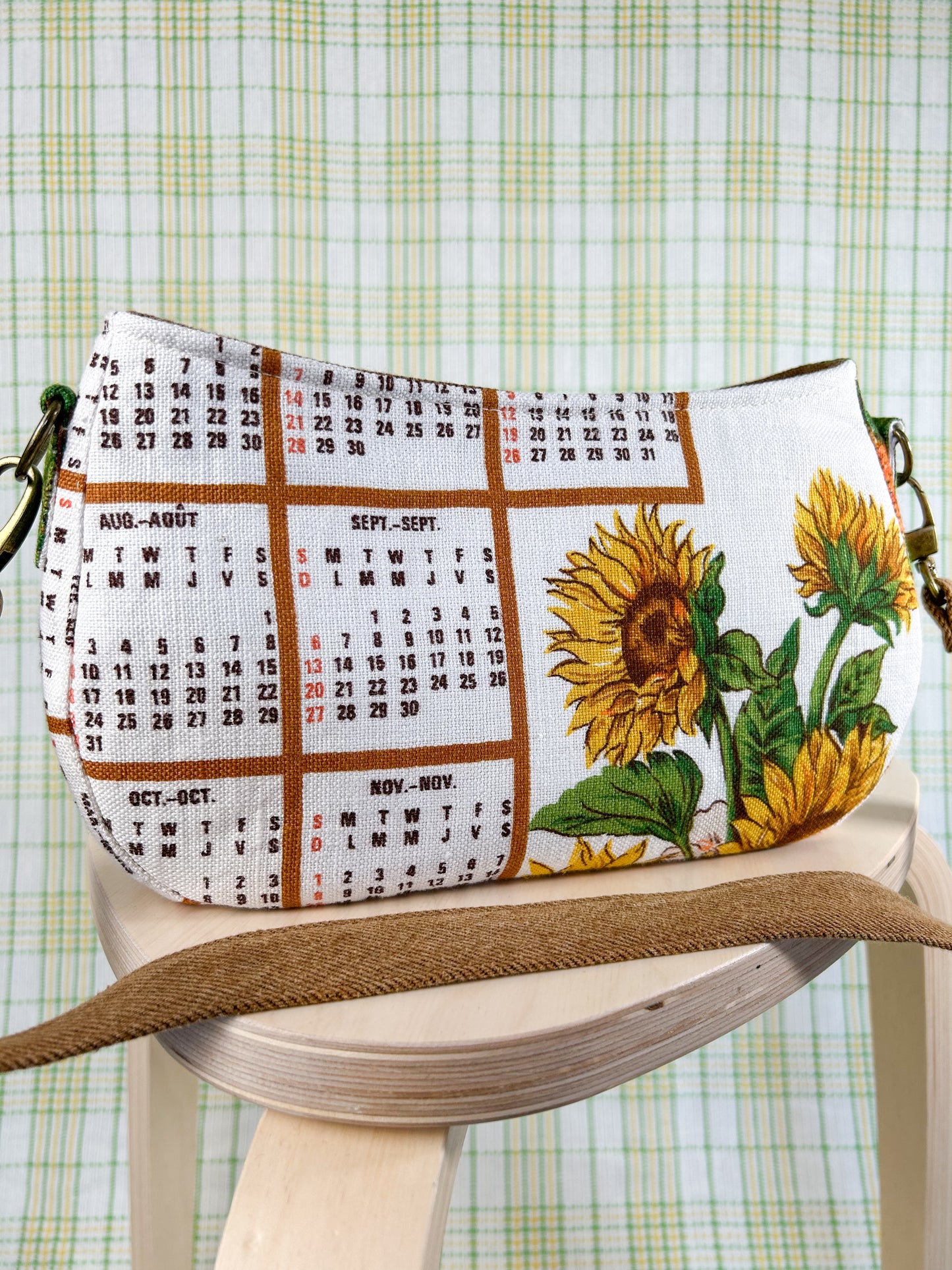 Handbag with sunflower and calendar design on a wooden stool against a plaid background