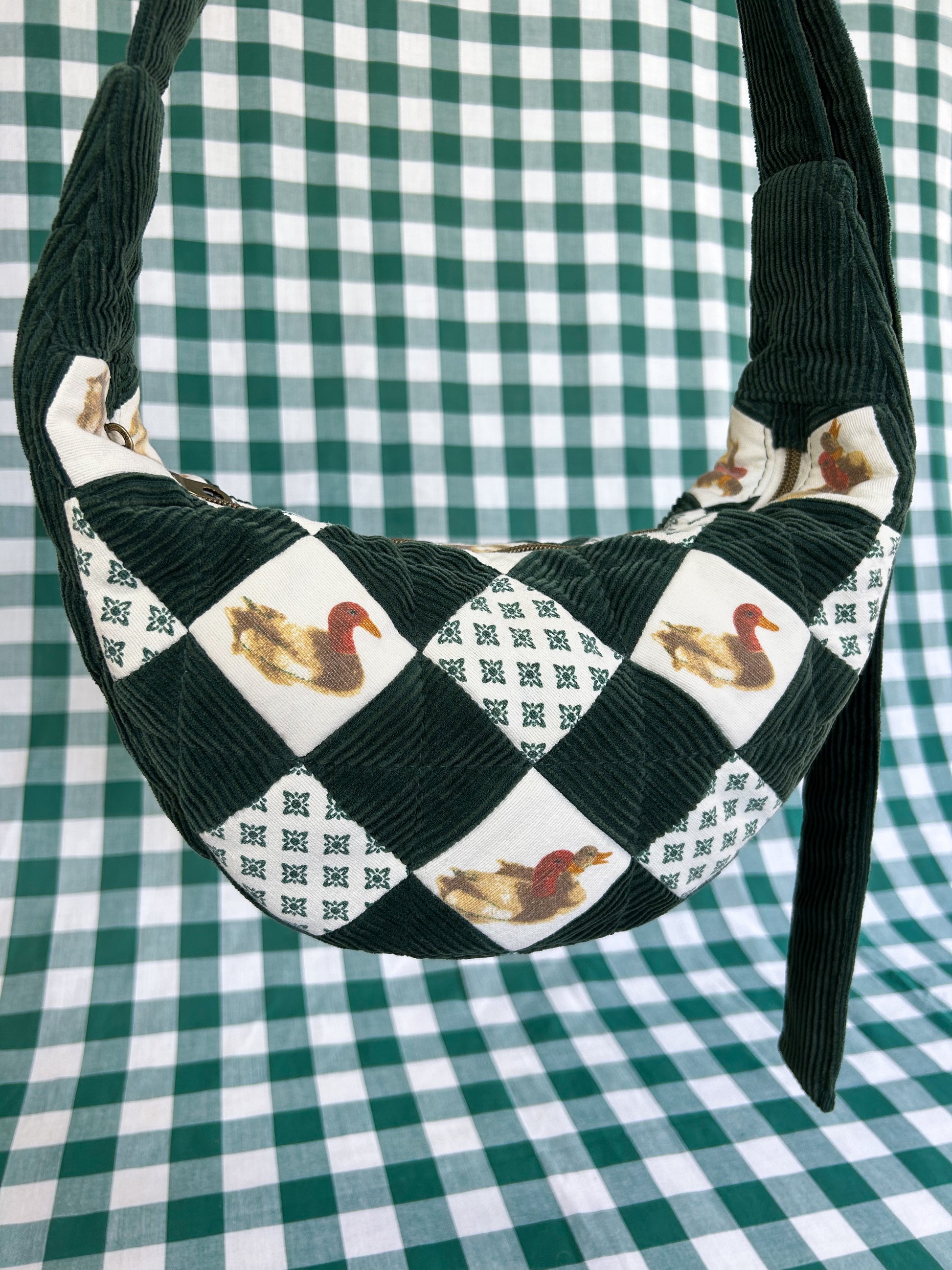 Close up of the same bag showing the quilted details and pattern on the front of the bag in front of a green and white gingham backdrop