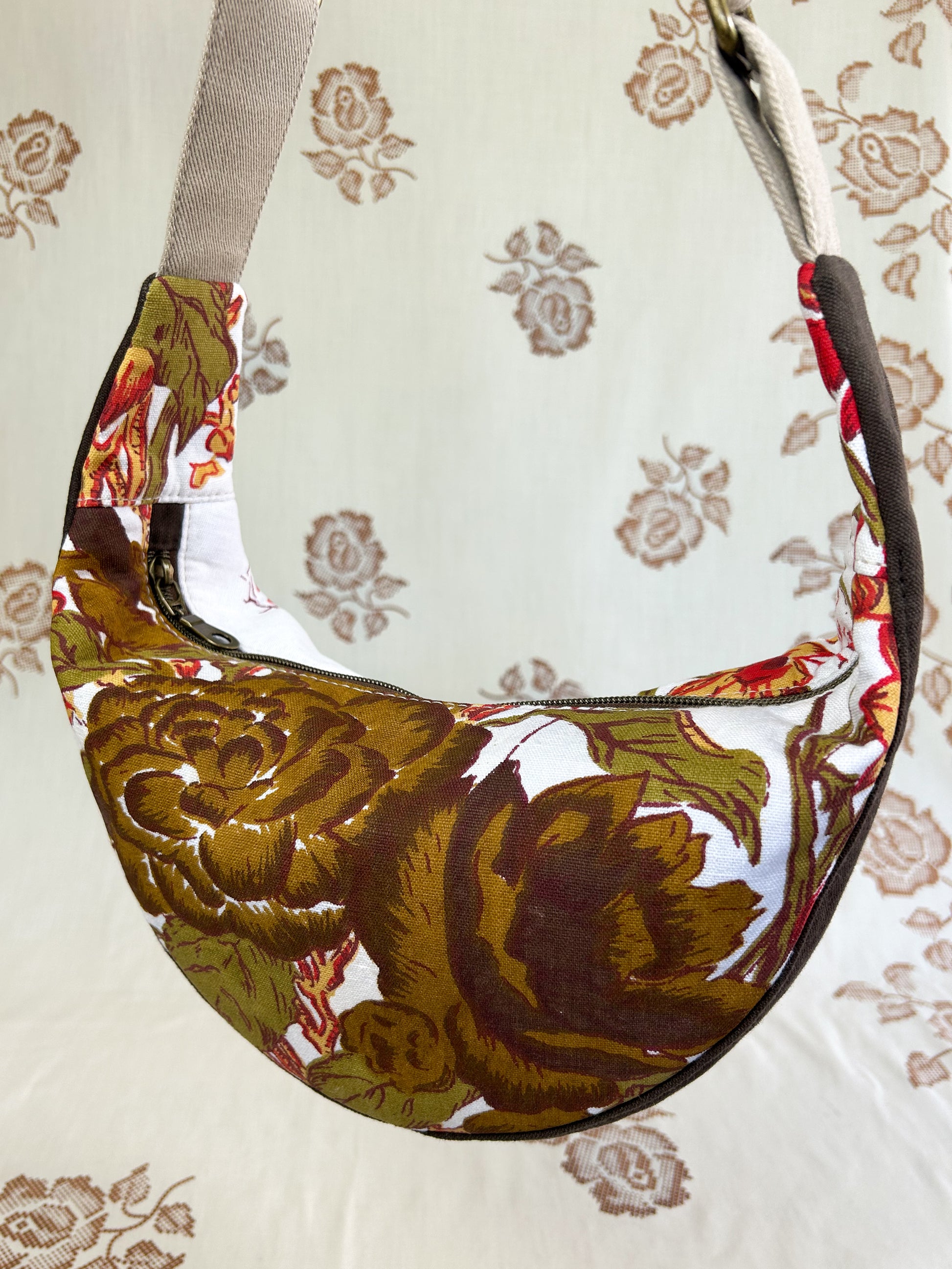 Close up of the same bag showing the pattern on the front hanging in front of a light cream coloured floral backdrop