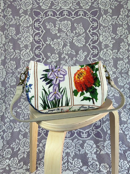Multi-colour floral-patterned handbag on a wooden stool against a lace-patterned background