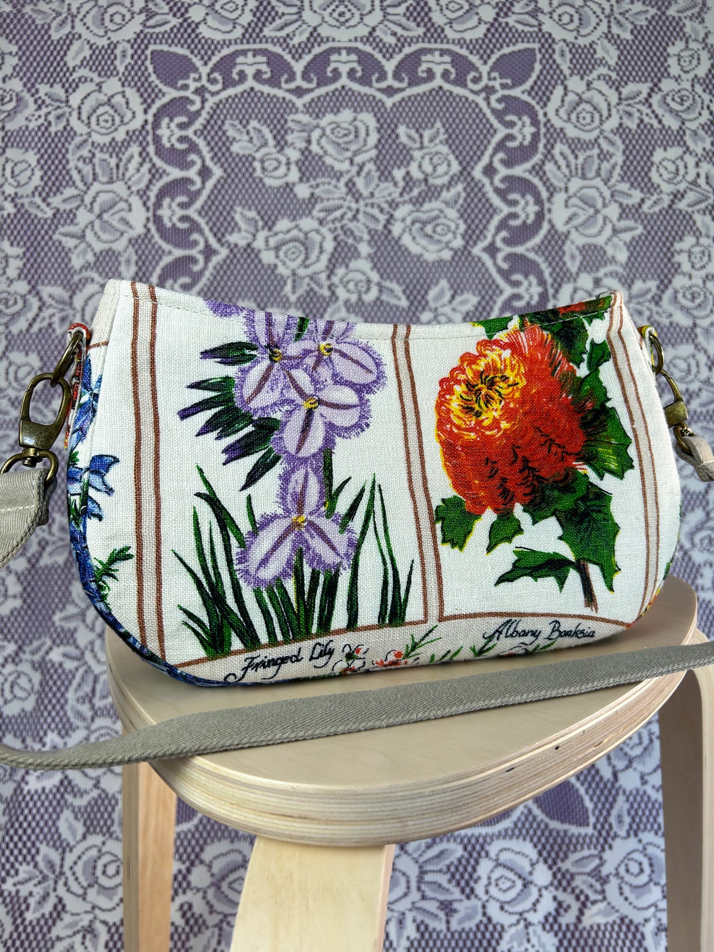 Closeup of the same handbag on a wooden stool against a lace-patterned background